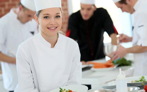 Koch-Auszubildende mit Kochmütze und Kittel in einer Küche
